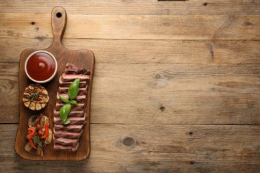 Ahşap masada baharatlı ve domates soslu leziz ızgara biftek. Metin için boşluk