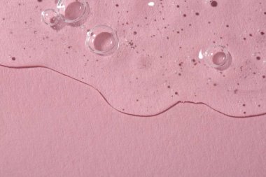 Pembe arka planda temiz kozmetik serumu, üst manzara. Metin için boşluk