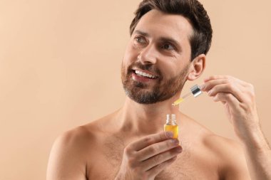 Bej arka planda kozmetik serumu olan yakışıklı bir adam, yakın plan. Metin için boşluk