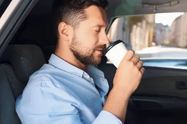 To-go drink. Handsome man drinking coffee in car