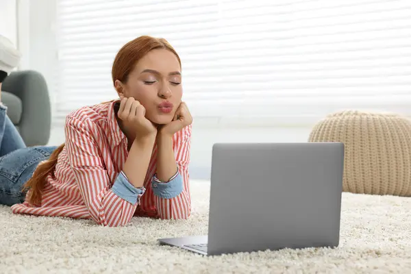 Woman sending air kiss during video chat via laptop at home. Long-distance relationship