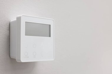 Beyaz duvarda bir termostat, mesaj için yer var. Akıllı ev sistemi