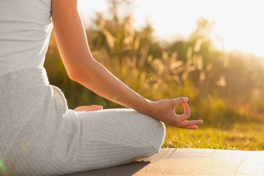 Dışarıdaki yoga minderinde Padmasana egzersizi yapan kadın, yakın plan. Lotus pozu