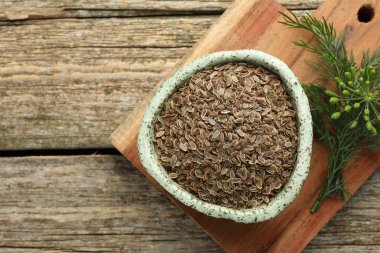 Tahta masanın üstünde kuru tohumlar ve taze dereotla dolu bir tahta tabağı var. Metin için boşluk