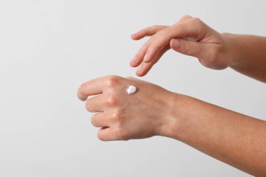 Beyaz arka planda kozmetik krem süren kadın, yakın plan.