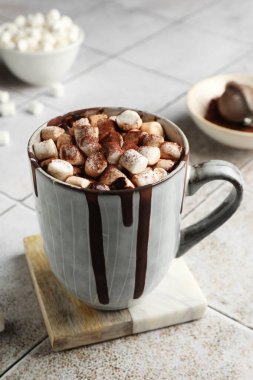 Marşmelovlu lezzetli sıcak çikolata ve fayanslı masada kakao tozu.