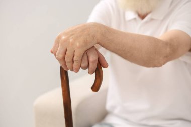Oturma odasındaki kanepede bastonlu son sınıf öğrencisi, yakın plan.