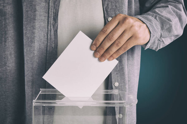 Человек кладет свой голос в урну для голосования на градиентном фоне, крупным планом