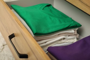 Çekmecede katlanmış farklı gömlek yığınları, yakın çekim. Giysileri düzenleme