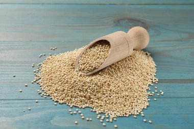 Açık mavi ahşap masada kepçe ve kuru kinoa tohumları