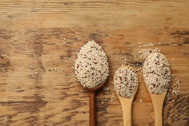 Tahta masanın üzerinde çiğ kinoa tohumları olan kaşıklar. Metin için boşluk