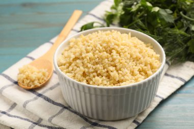 Açık mavi ahşap masada kasede leziz bulgur, yakın plan.