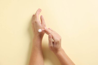 Bej arka planda kozmetik krem süren kadın, üst görünüm