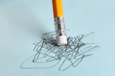 Açık mavi arkaplanda grafit kalem ile karalamalar siliniyor, yakın plan