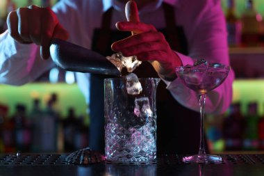 Alkolik kokteyl yapmak. Barmen bardaki bardağa buz küpleri ekliyor, yakın plan.