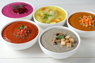 Lezzetli çorba ve beyaz ahşap masada farklı krema çorbaları, yakın plan.