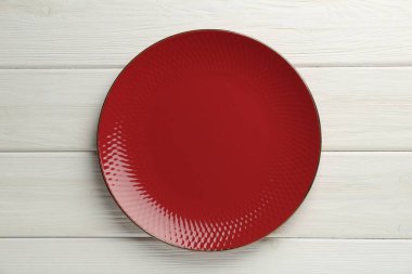 Beyaz ahşap masada güzel kırmızı seramik tabak, üst manzara.