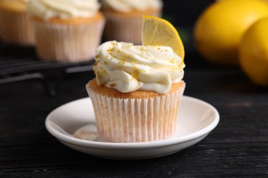 Siyah ahşap masada beyaz kremalı lezzetli limonlu kekler, yakın plan.