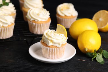 Beyaz kremalı, limonlu ve siyah ahşap masada limonlu lezzetli kekler, yakın plan.