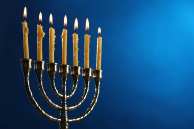 Hanuka kutlaması. Mavi arkaplanda mum yakan Menorah, metin için yakın plan ve boşluk