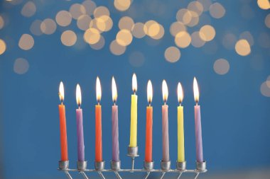 Hanuka kutlaması. Mor arkaplanda yanan mumlar ve bulanık ışıklar olan menorah.