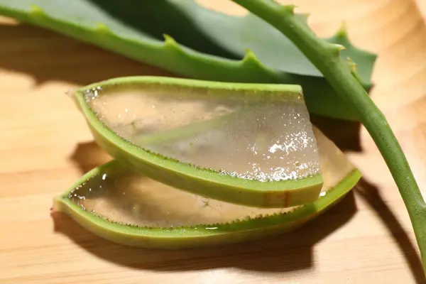 stock image Slices of fresh aloe vera leaves with gel on wooden table, closeup