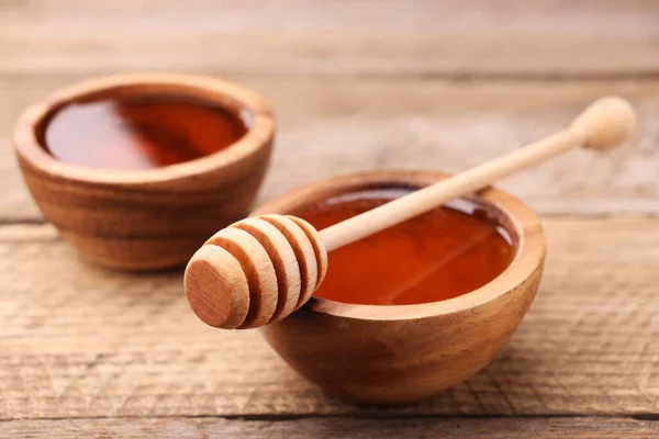 Delicious honey in bowls and dipper on wooden table