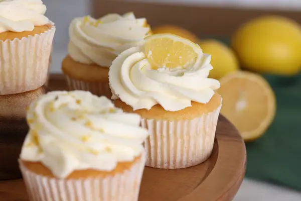 Delicious lemon cupcakes with white cream on wooden stand, closeup