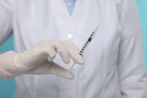 Doctor holding syringe with needle, closeup view