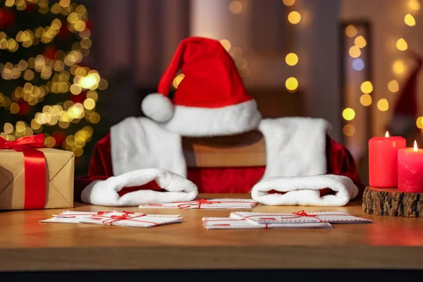 Santa\'s Claus workplace. Gift boxes, letters on table and costume in room with Christmas tree