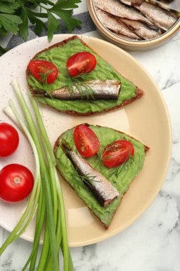 Lezzetli sandviçler, sprat, domates, avokado püresi ve dereotlu beyaz mermer masa, düz uzanmış