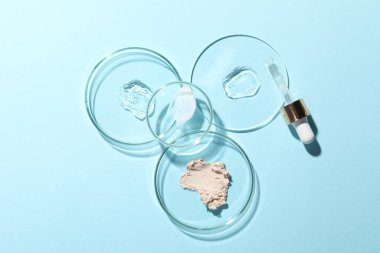Pipette, kozmetik serumu ve üzerinde açık mavi arkaplan örnekleri olan petri kapları.