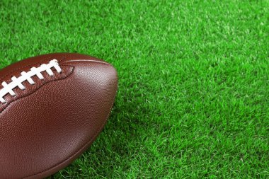 Amerikan futbol topu yeşil çimlerin üzerinde, yakın plan. Metin için boşluk