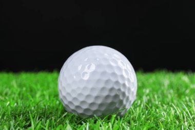 Siyah arka plana karşı yeşil çimlerde golf topu, yakın plan