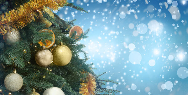 Christmas tree decorated with golden festive balls against blurred background, bokeh effect. Banner design with space for text