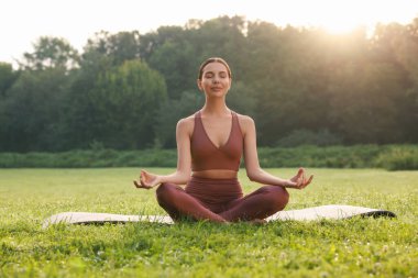Güzel genç bir kadın yoga minderinde Padmasana egzersizi yapıyor. Lotus pozu