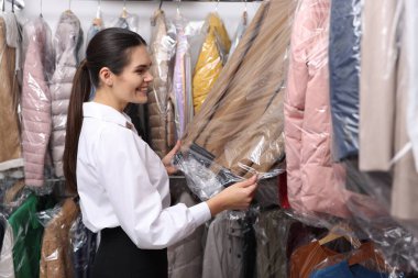 Kuru temizleme servisi. Mutlu işçi, içerideki askılardan kıyafet seçiyor.