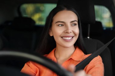 İyi yolculuklar. Arabasını kullanan mutlu genç bir kadın, ön camdan manzaralı.