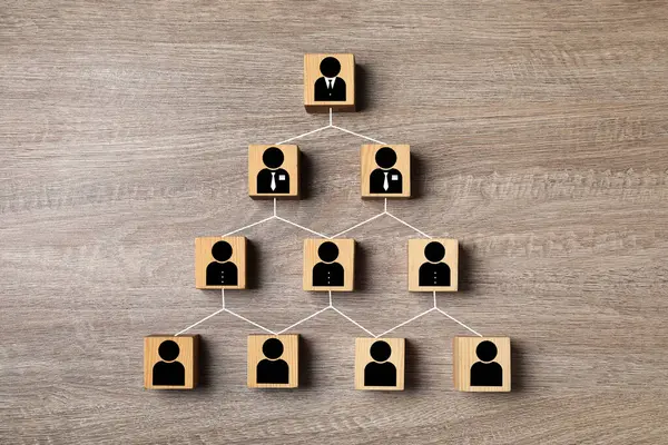 Team management. Cubes with human icons linked together symbolizing company structure on wooden table, top view