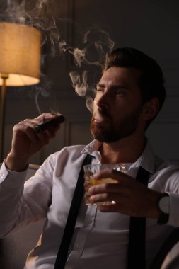 Evde puro içen yakışıklı bir adam.