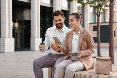 İş yemeği. Mutlu iş arkadaşları teneffüste dışarıda bankta birlikte vakit geçiriyorlar.