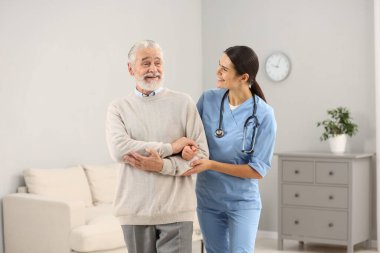 Hastanede yaşlı hastalara bakan gülümseyen hemşire.