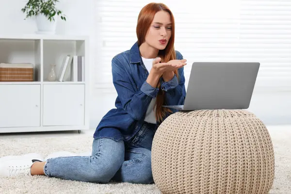 Woman blowing kiss during video chat via laptop at home. Long-distance relationship