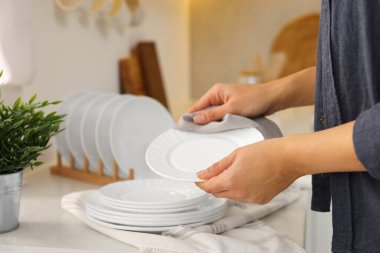 Kadın mutfakta havluyla tabağı siliyor, yakın plan.