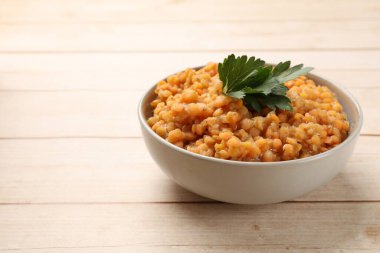 Ahşap masada maydanozlu lezzetli kırmızı mercimekler, yakın plan. Metin için boşluk