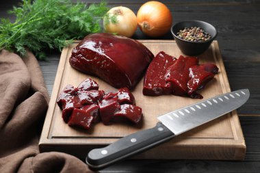 Çiğ sığır ciğerini soğan, dereotu ve baharatla ahşap masada kes.