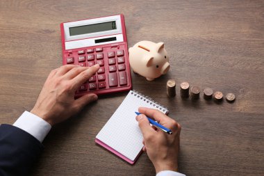 Bütçe planlaması. Not defterini ahşap masa üzerinde hesaplayan bir iş adamı.