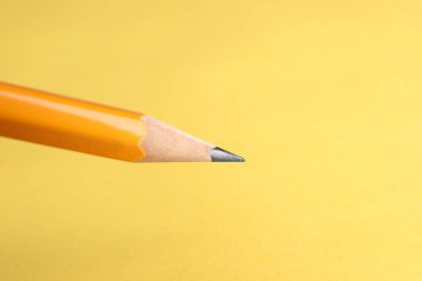Sarı arka planda keskin bir grafit kalem, yakın plan. Metin için boşluk