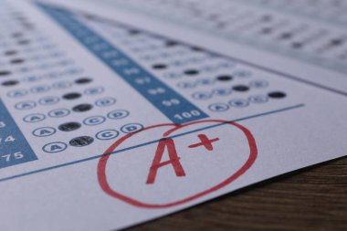 Okul derecesi. Kırmızı harfli cevap kağıdı A ve artı sembolü ahşap masada, yakın plan.