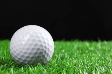 Siyah arka plana karşı yeşil çimlerde golf topu, yakın plan. Metin için boşluk